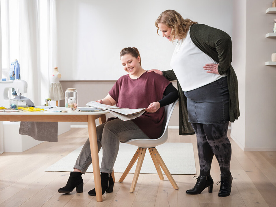 Two women are looking at a magazine together