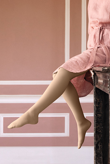 7. Lifestyle Bild Juzo Soft Frau mit Juzo Soft Sesam sitzt auf einem Kaminsims