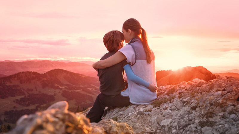 Una madre está sentada con su hijo en la cima de una montaña. El niño lleva una manga de compresión. Una madre está sentada con su hijo en la cima de una montaña. El niño lleva una manga de compresión.
