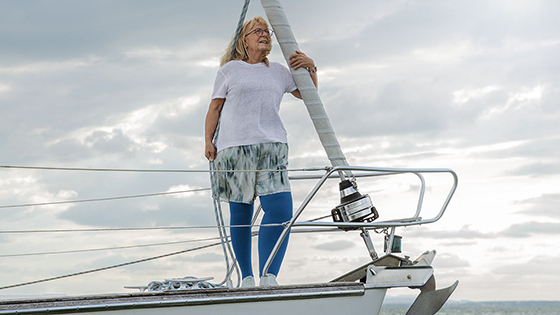 A woman with lymphoedema is standing on the deck of a boat. She is wearing blue compression stockings A woman with lymphoedema is standing on the deck of a boat. She is wearing blue compression stockings