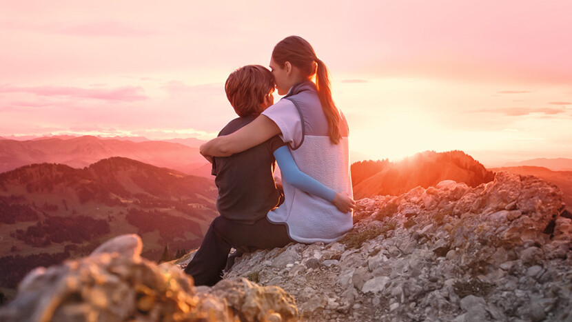 Une mère est assise avec son enfant au sommet d'une montagne. L'enfant porte une manchette de compression.