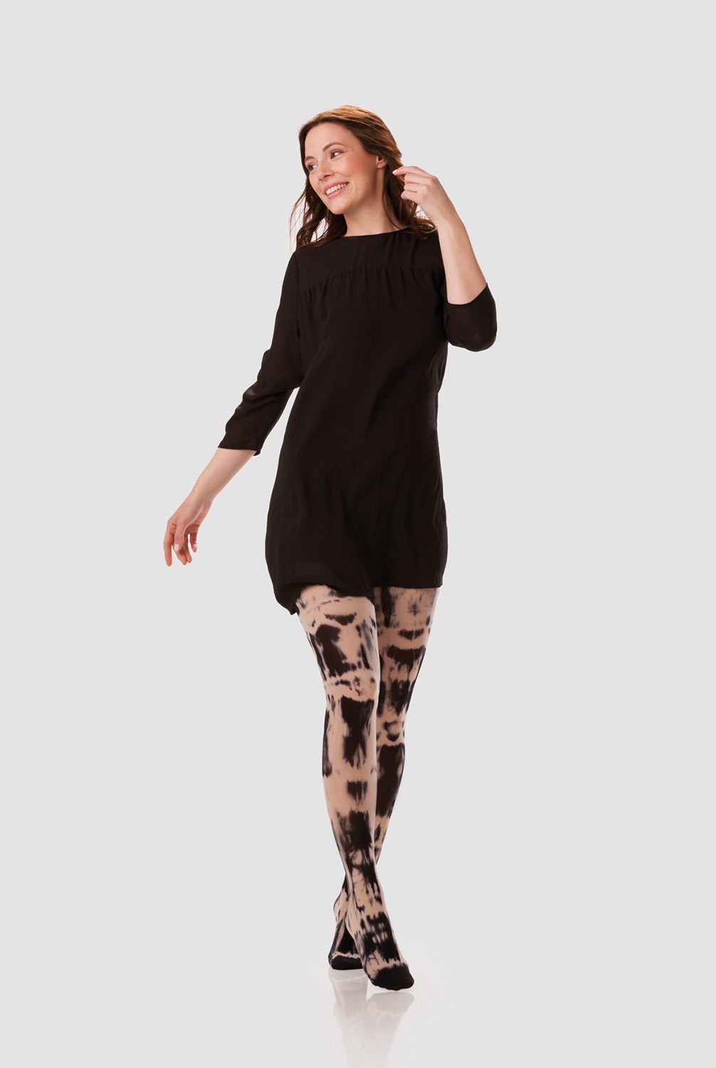A woman is wearing a black long-sleeved dress with a compression garment in black and sesame batik