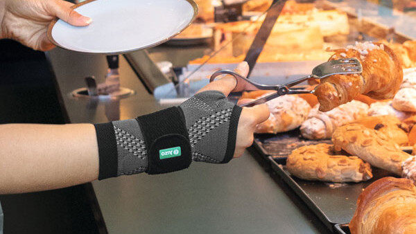 Eine Verkäuferin in der Bäckerei trägt eine Handgelenkbandage bei der Arbeit