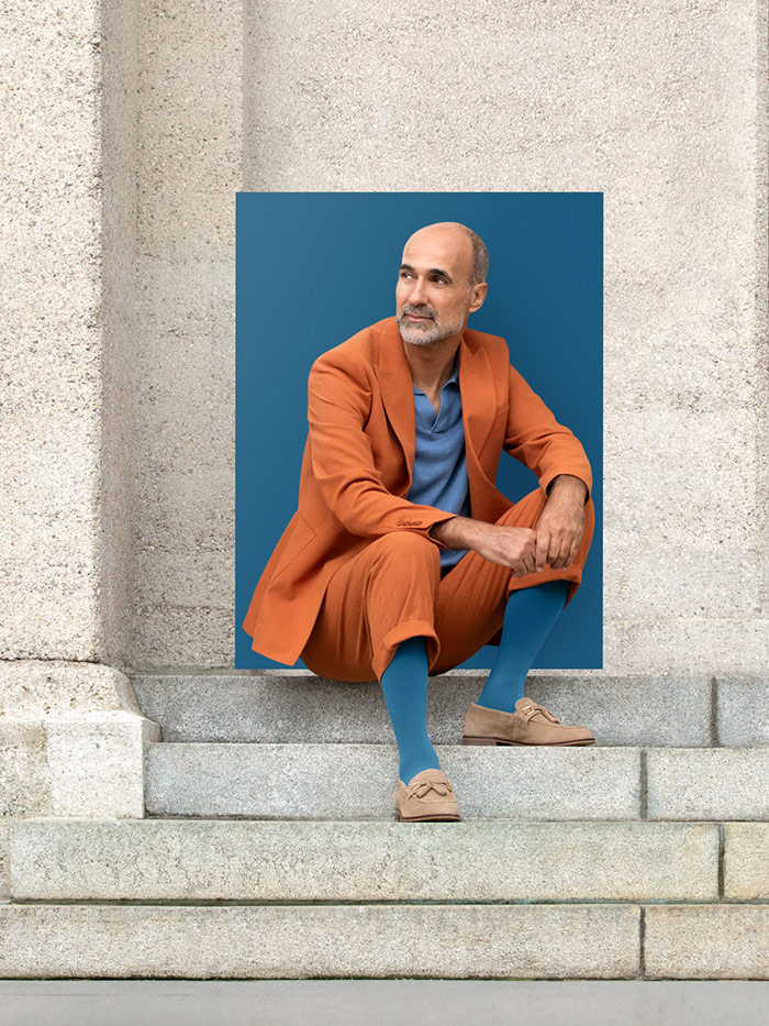 A man sits on steps in the city wearing a Casual Blue compression garment with a relaxed orange suit